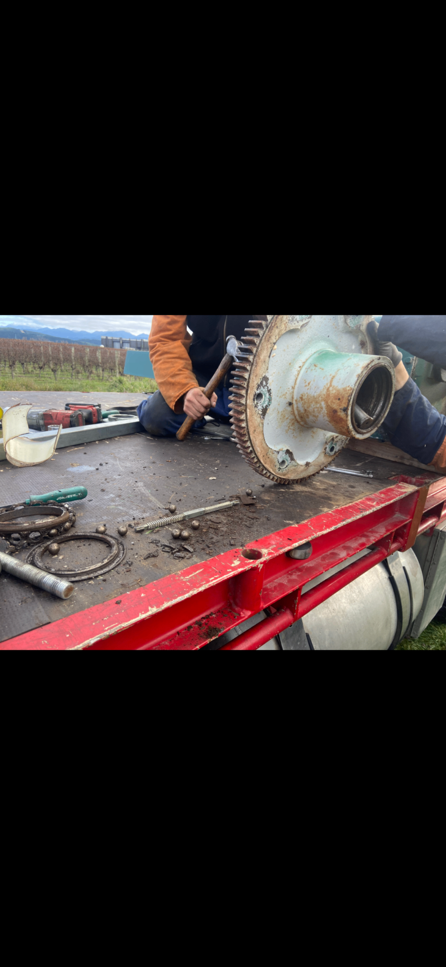 Technician repairing a frost fan gearbox and drive components on site
